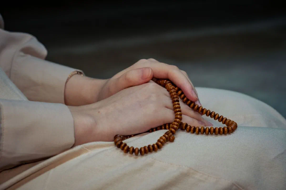 Close-up of hands holding wooden prayer beads, symbolizing spirituality and meditation.