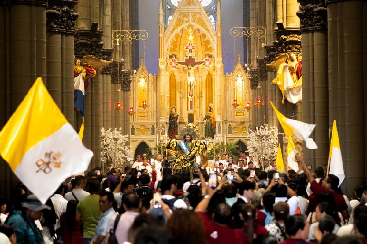 Crowd celebrates during a colorful religious ceremony inside a grand cathedral.