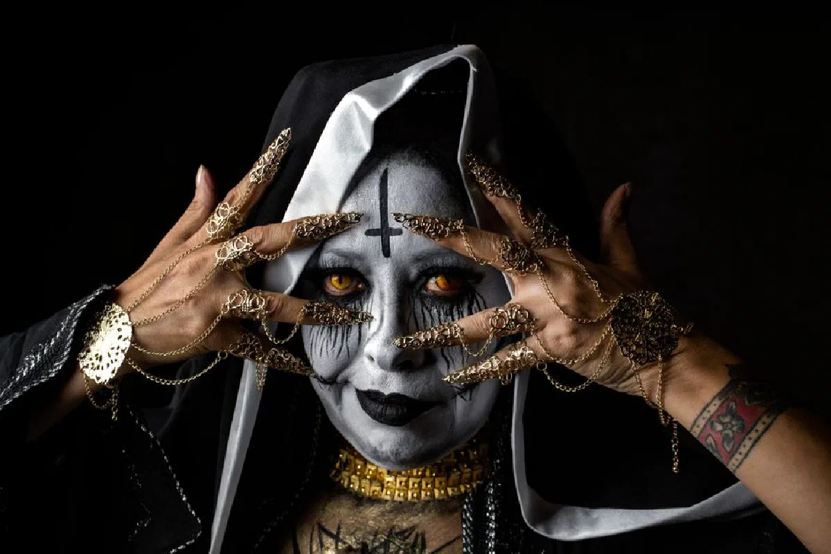 Close-up of a person with dramatic gothic makeup and elaborate finger jewelry creating a mysterious look.