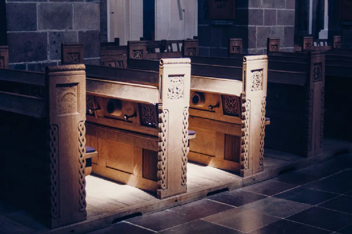 Beautifully carved wooden pews inside a dimly lit church, highlighting architectural elegance.
