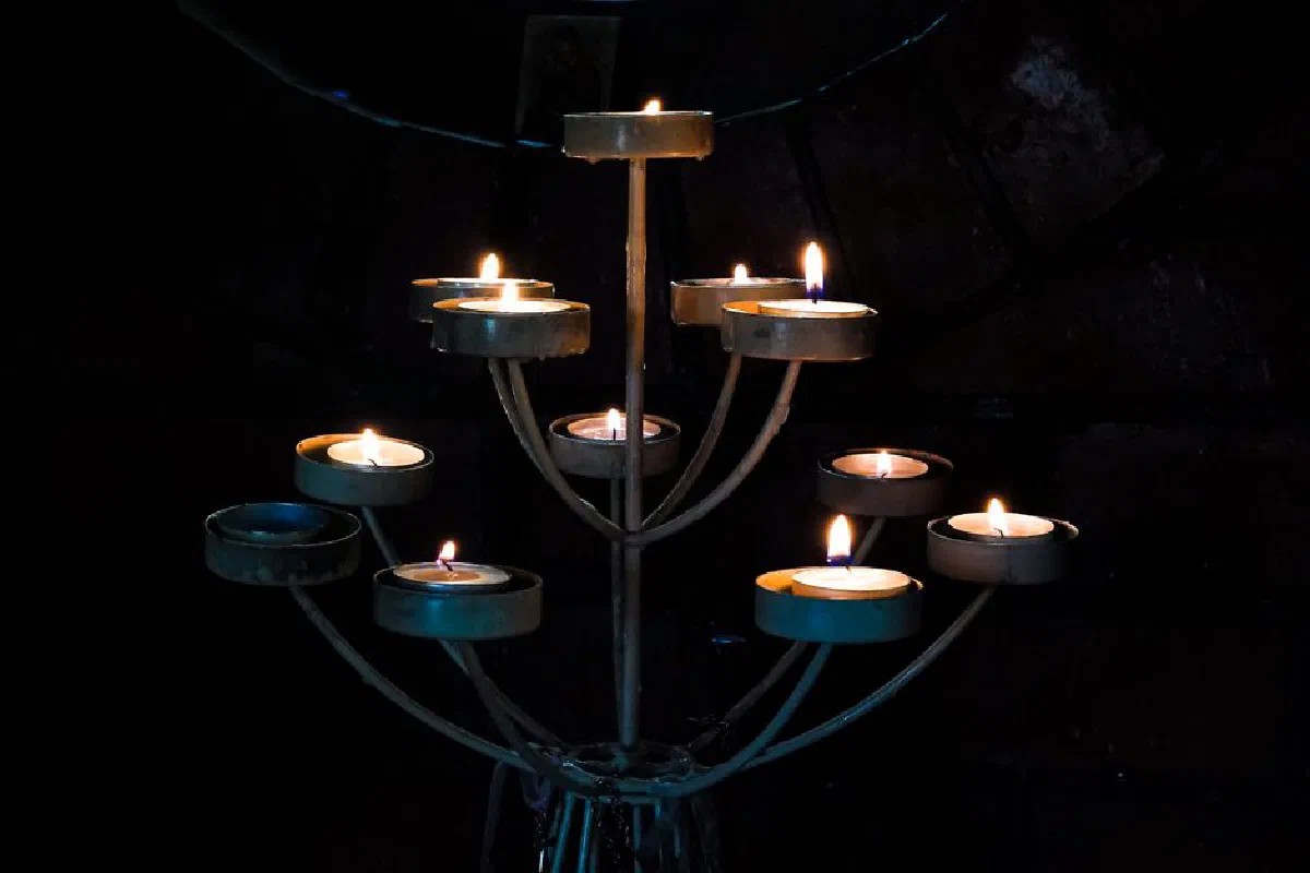 A dramatic and elegant candleholder featuring multiple lit tealights against a dark background.