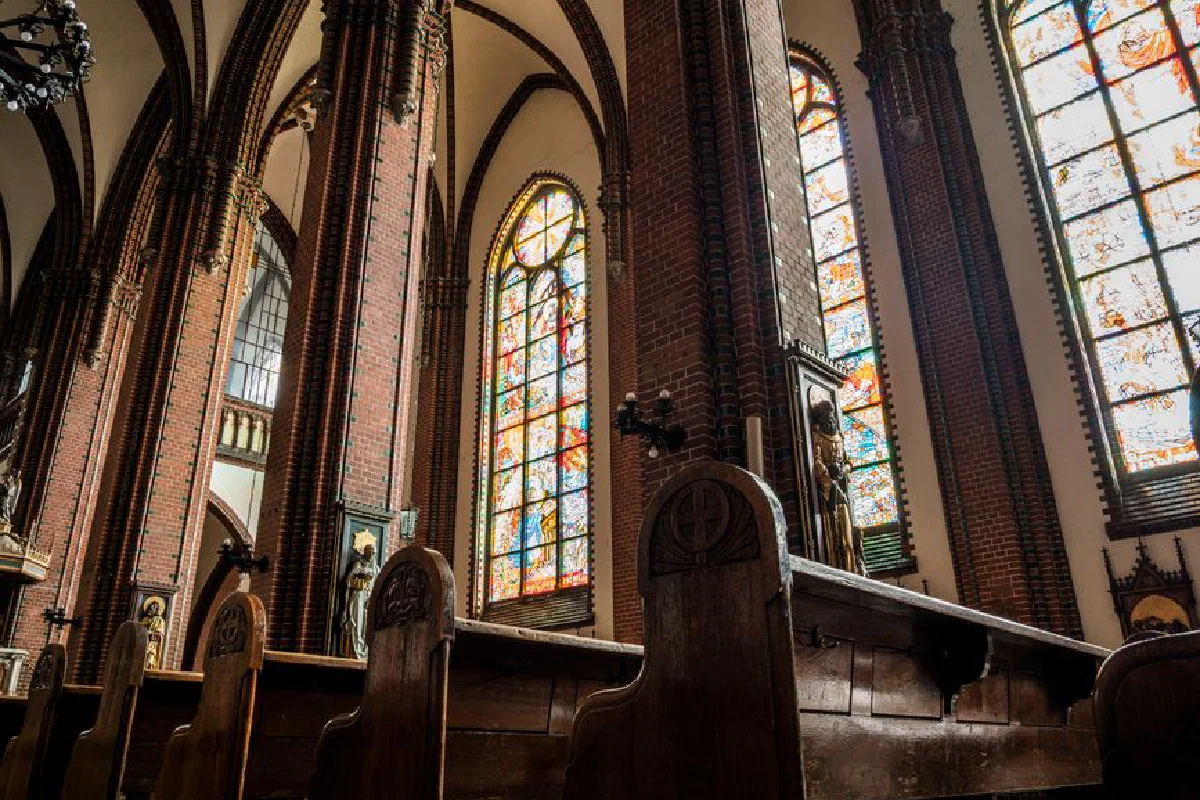 Detailed view of a Gothic cathedral interior featuring stunning stained glass windows and wooden pews.