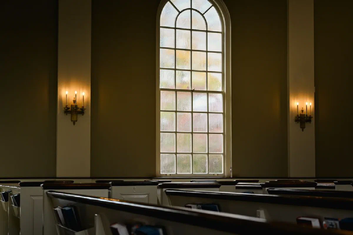 Spacious church interior with stained glass window and traditional pews, invoking serenity.