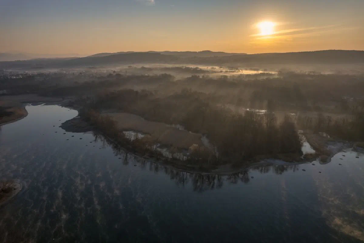 A breathtaking aerial view of a tranquil lake and misty landscape at sunrise, capturing the essence of nature's beauty.
