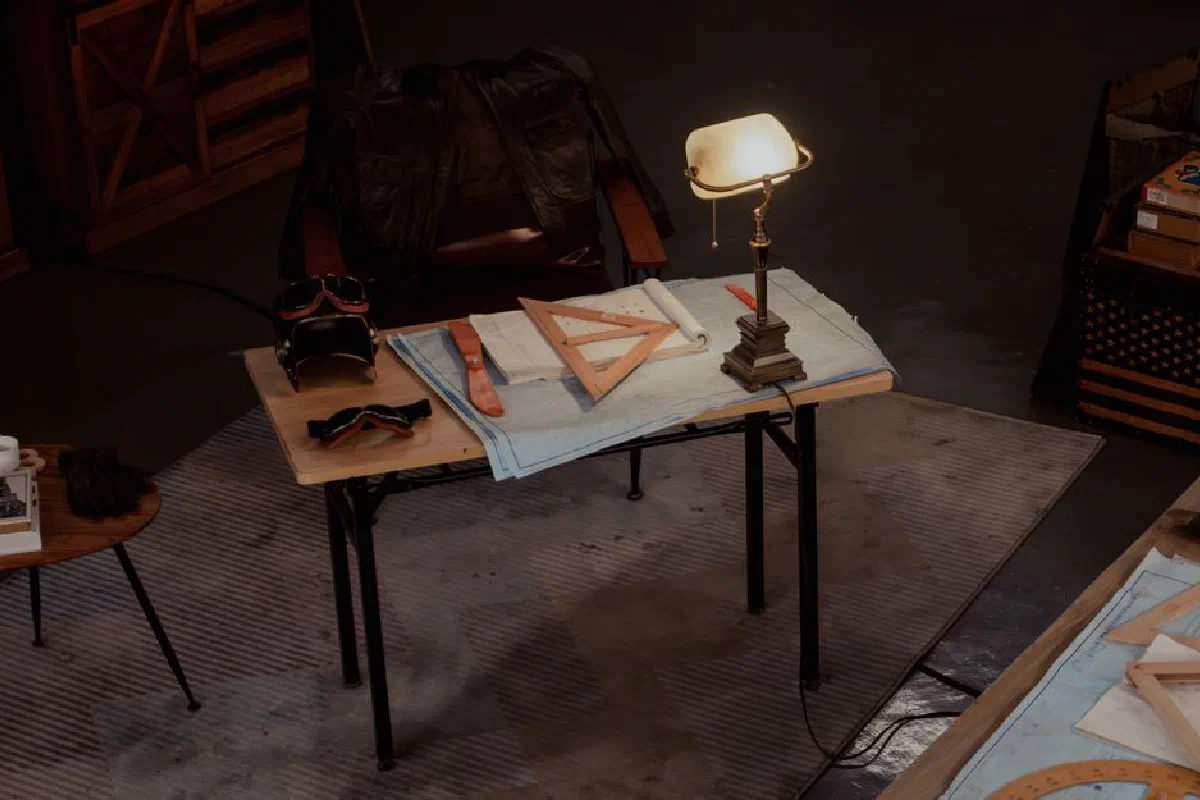 A cozy vintage studio showcasing drafting tools, a lamp, and retro elements on a desk.