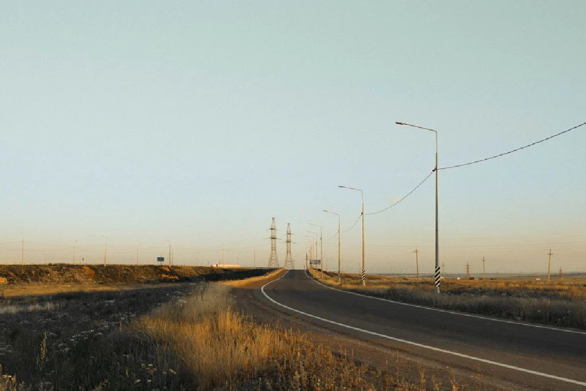 A deserted rural road stretches into the horizon during a serene sunset, offering a peaceful travel vibe.