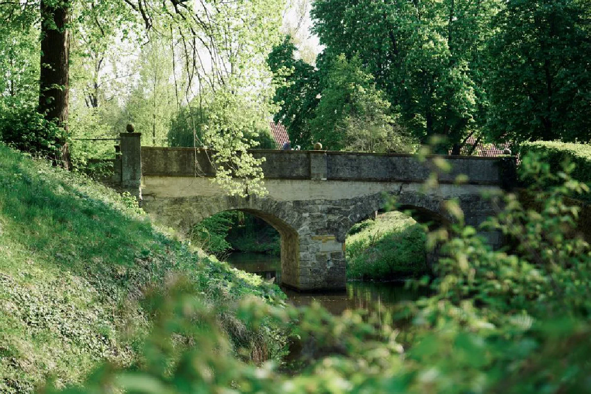 Charming stone bridge surrounded by lush greenery in Rheda-Wiedenbrück, Germany, on a sunny spring day.
