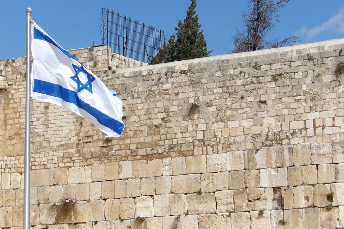 Israeli flag waving at the historic Western Wall, a significant religious site in Jerusalem.