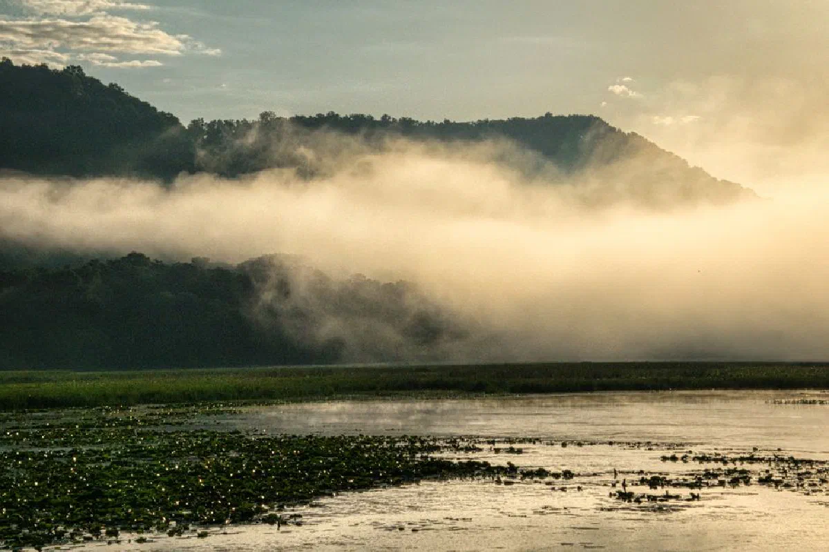 Serene misty morning over a lake and hills in Alma, Wisconsin, capturing fog and calm waters.