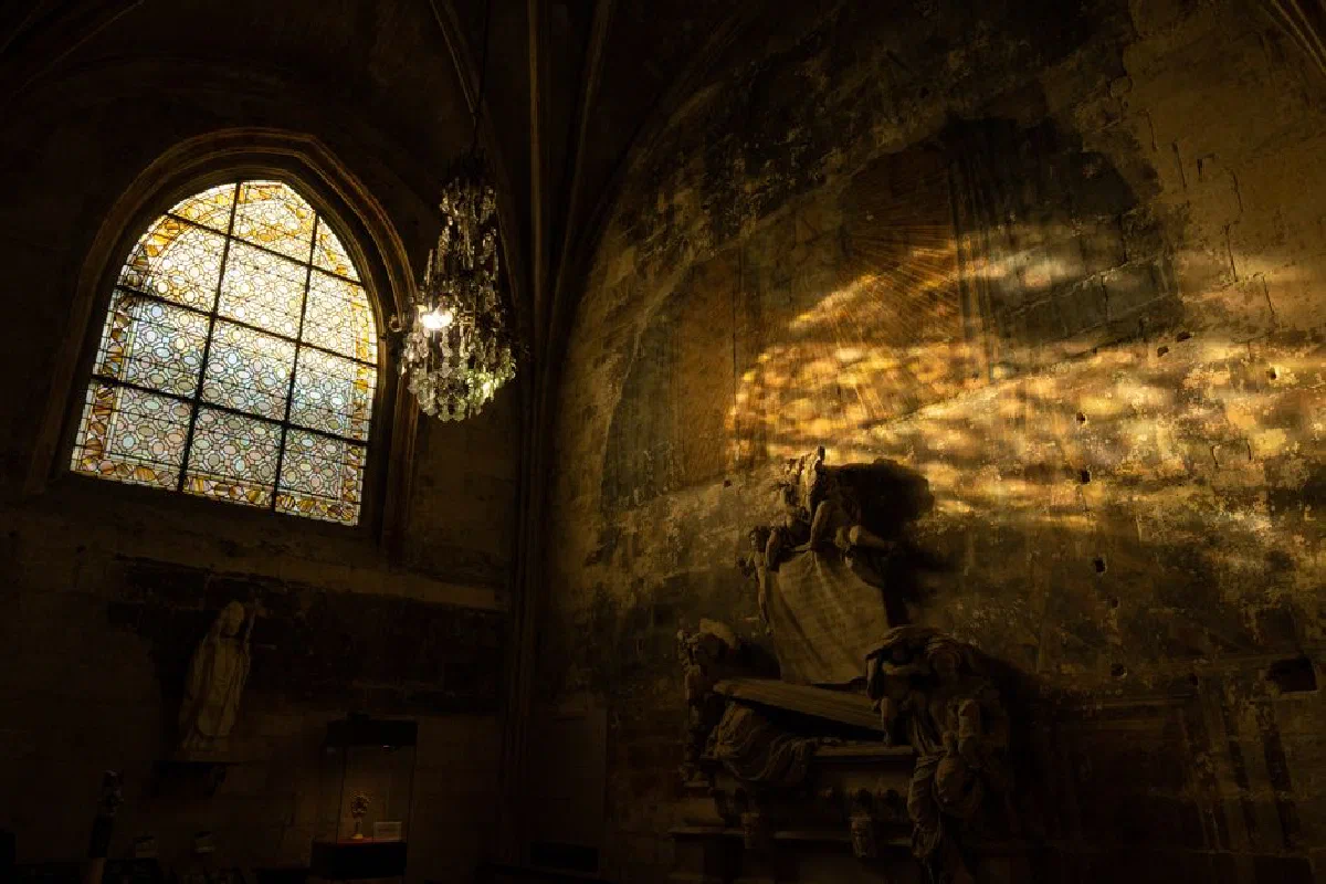 Sunlight through stained glass illuminates a chapel interior in Arles, France.