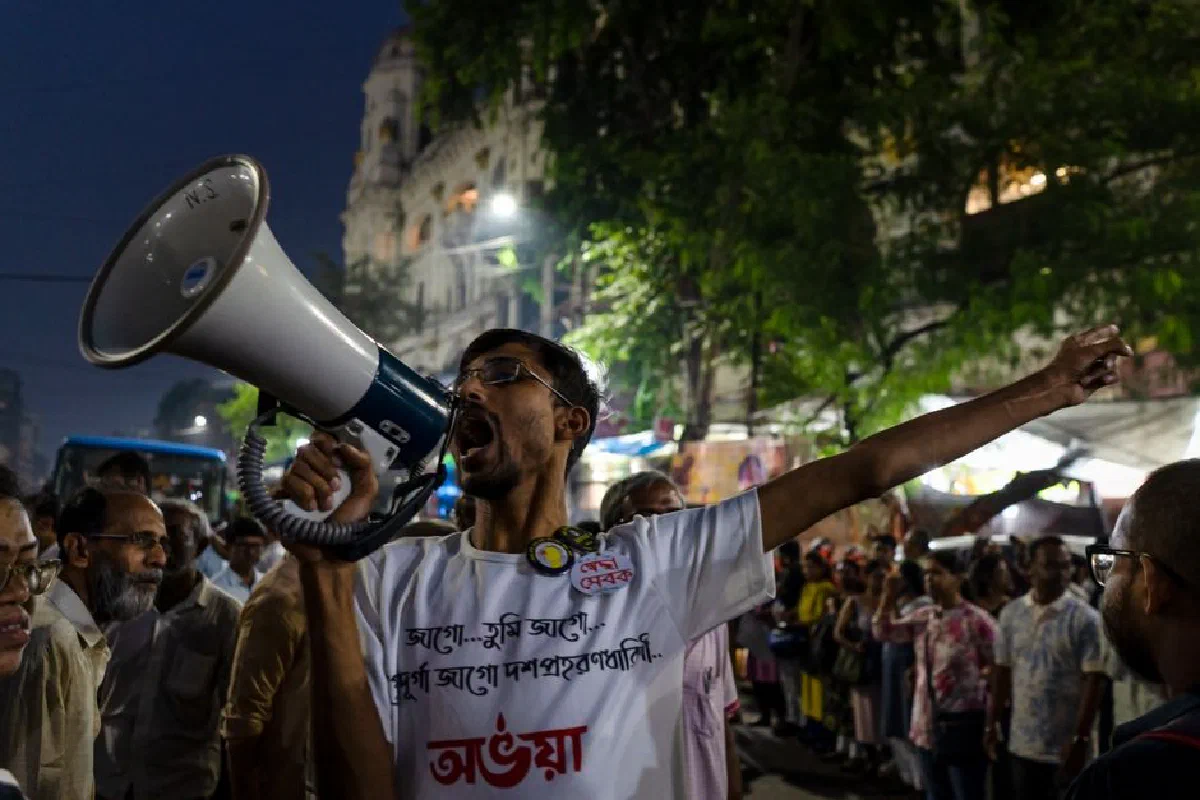 Man with megaphone leading a protest in a city at night, engaging crowd with public speaking.
