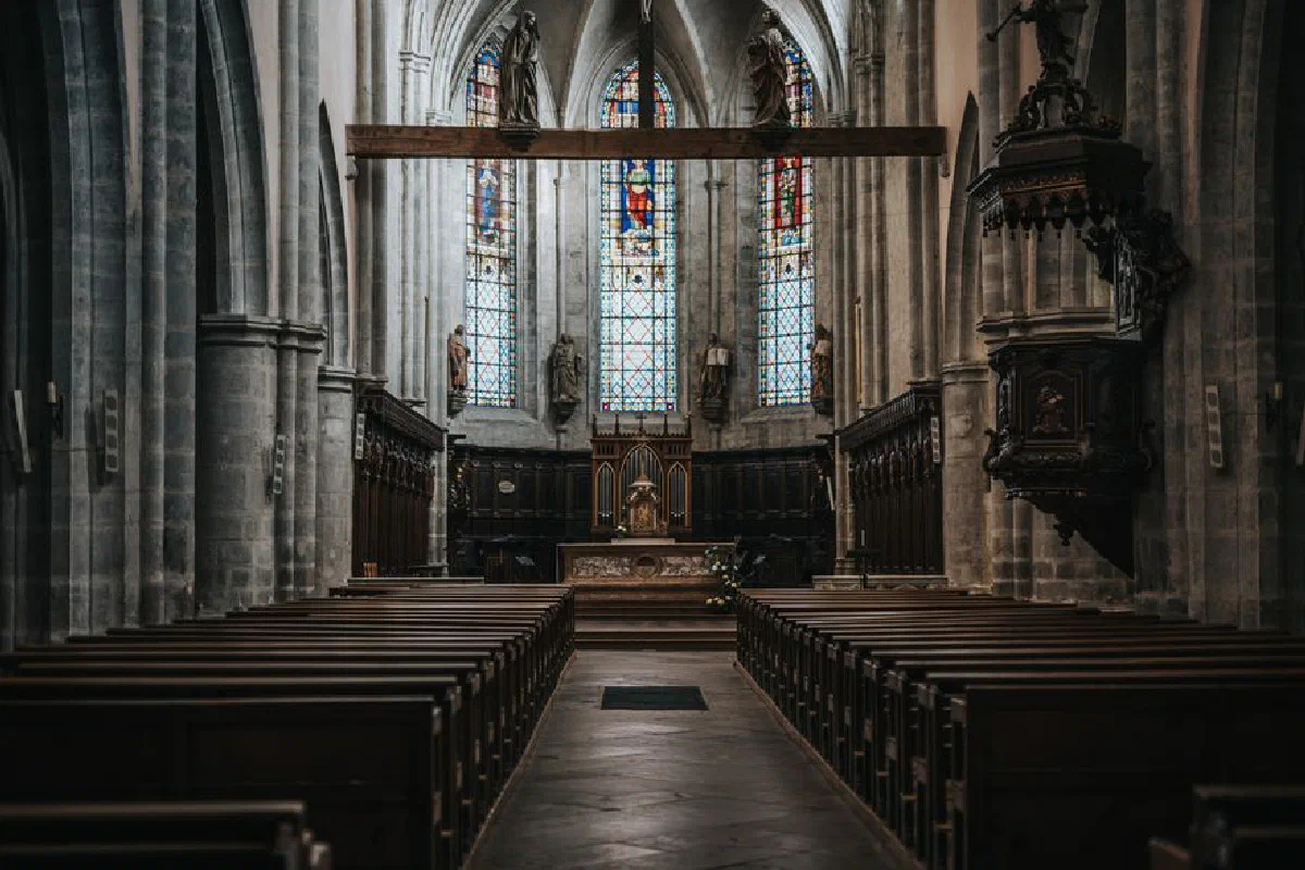 A beautifully captured interior of a historic Gothic church with stained glass windows and wooden pews.