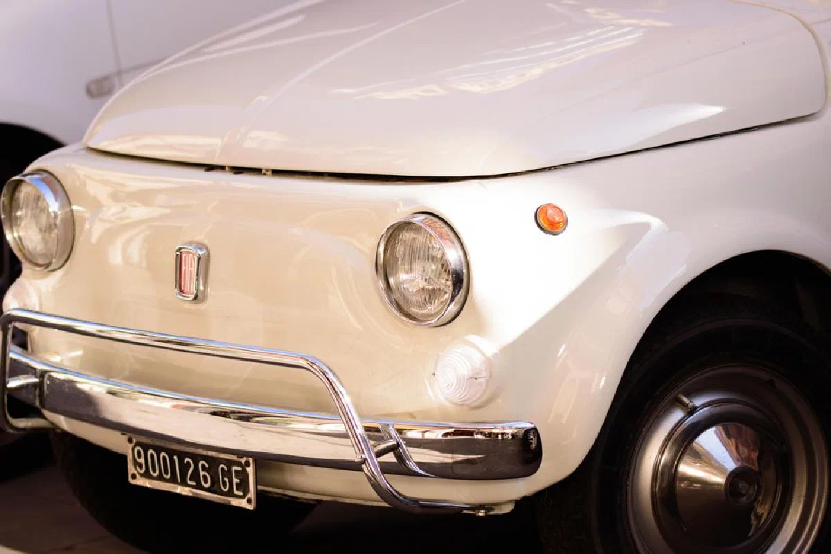 Front view of a classic white Fiat car showcasing shiny chrome details and vintage design elements.