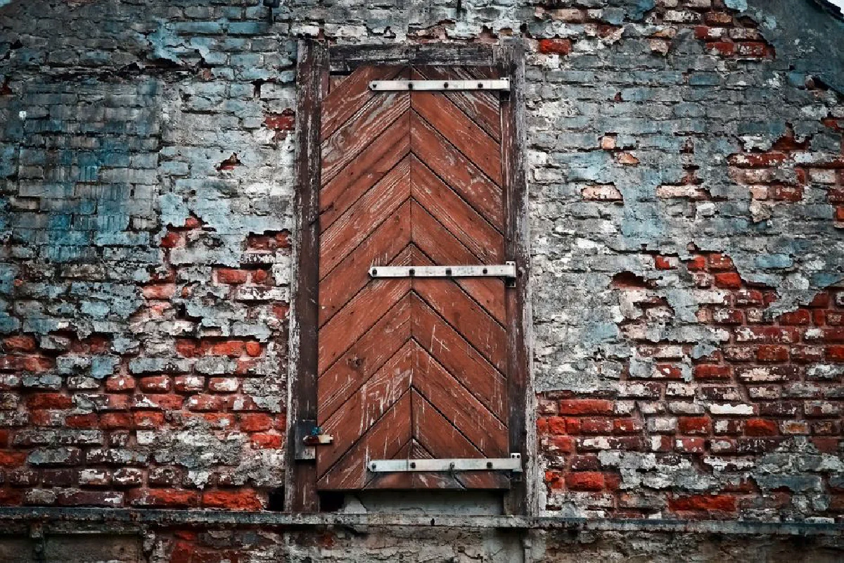 Rustic wooden door set in a weathered brick wall, showcasing vintage architecture.
