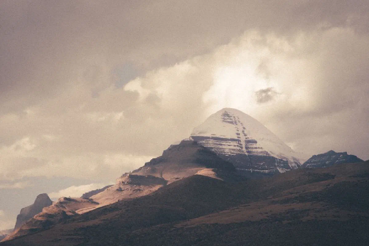 A serene snow-capped mountain peak illuminated by the setting sun under dramatic skies.