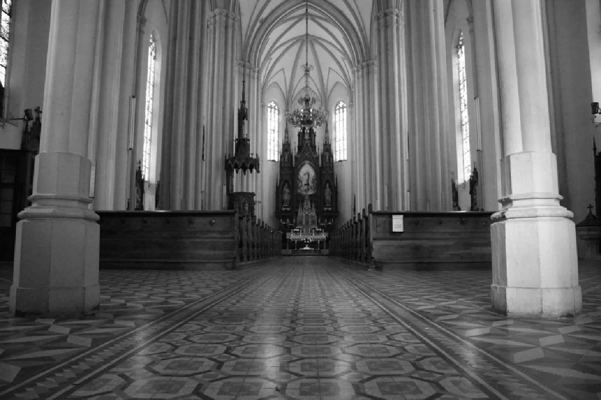 Black and white spacious empty Catholic Church hallway with columns and majestic shrine under arched roof