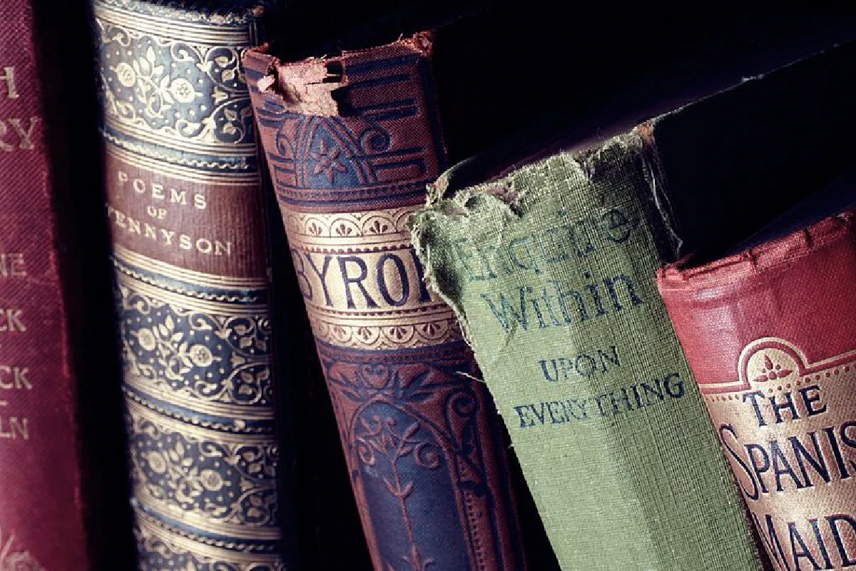 Close-up of vintage leather-bound books with ornate designs on a bookshelf.