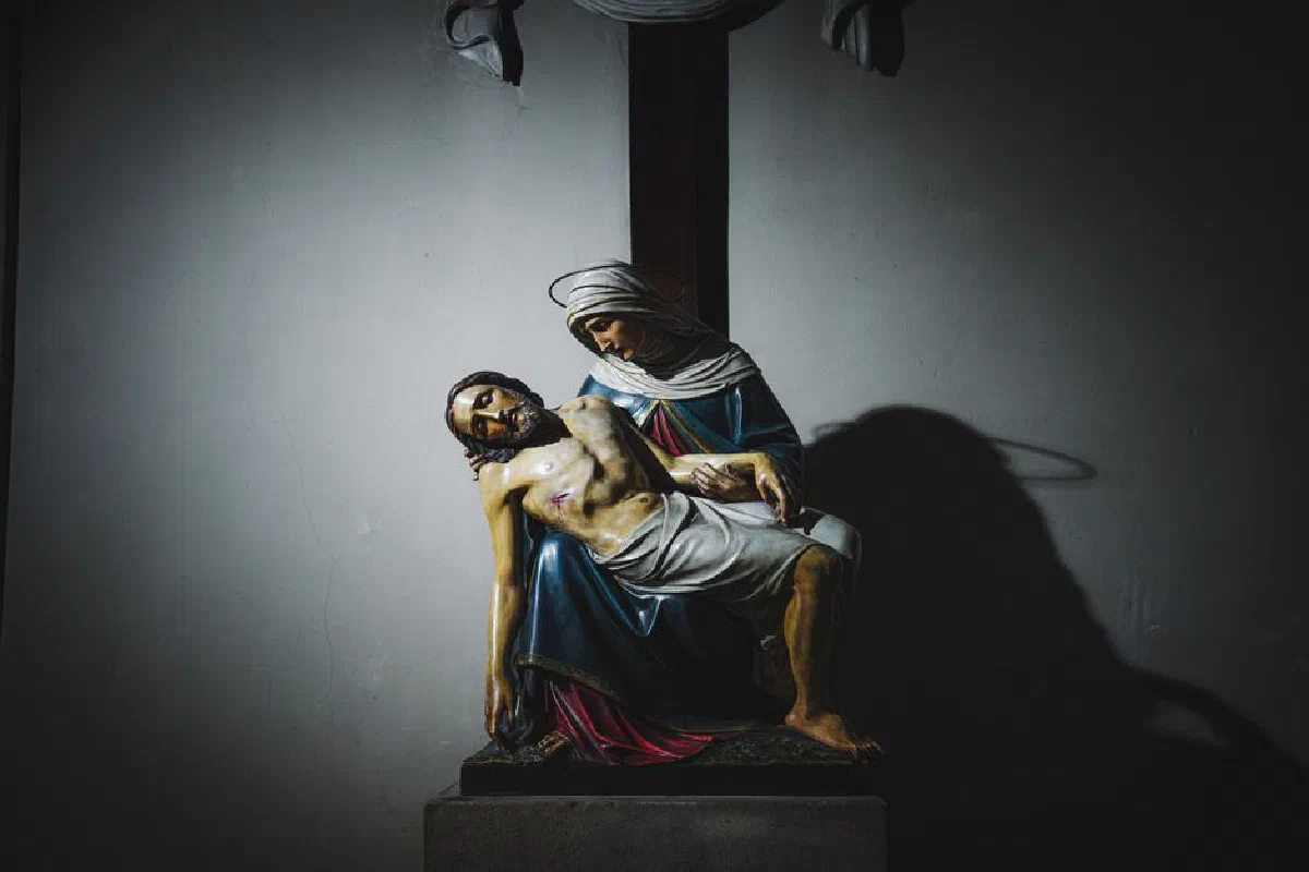 A low-light photograph of a religious sculpture depicting Jesus and the Virgin Mary, emphasizing the theme of Christianity.