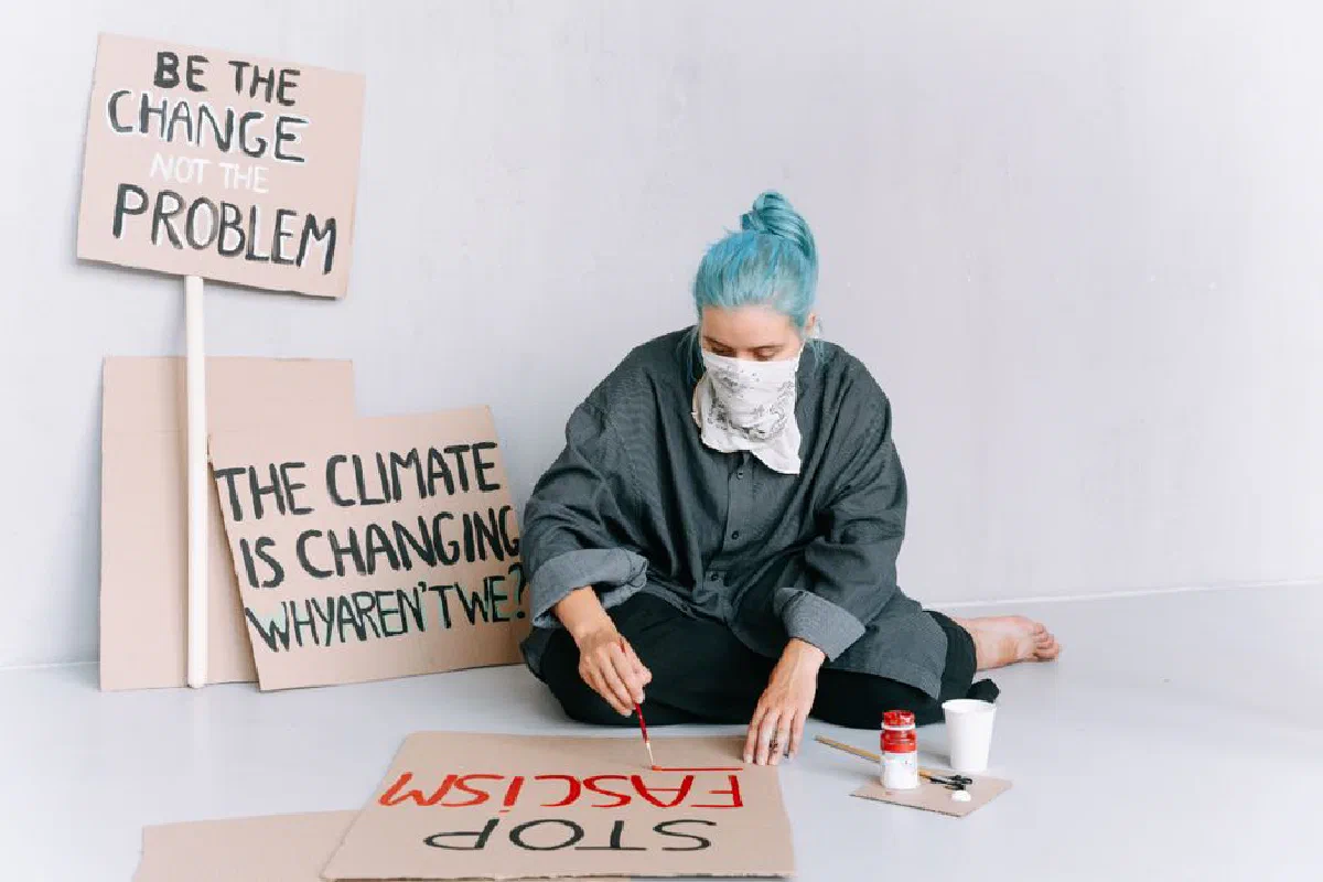 A woman paints protest signs with messages on climate change and social activism.