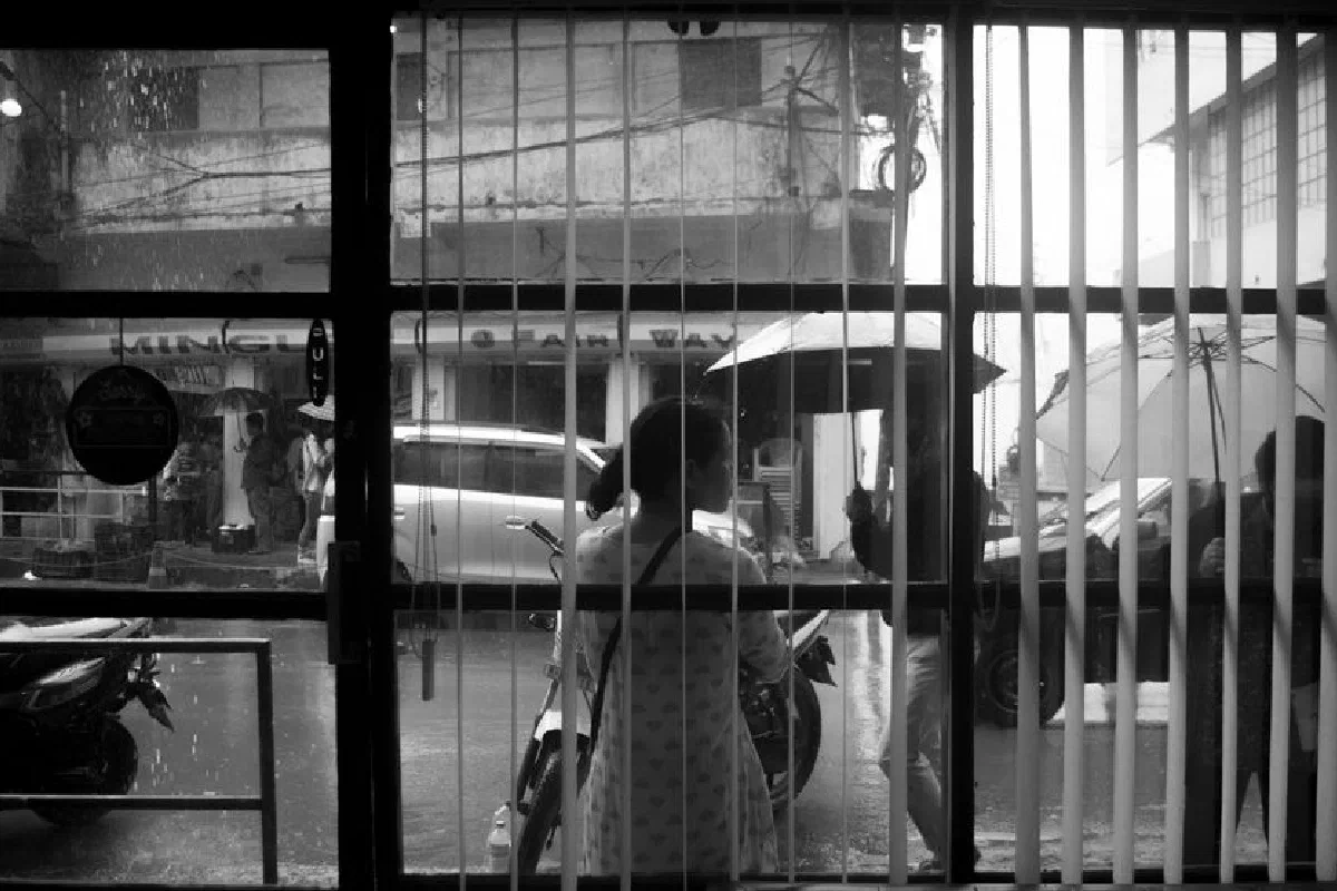 A black and white street view captured through a window on a rainy day.