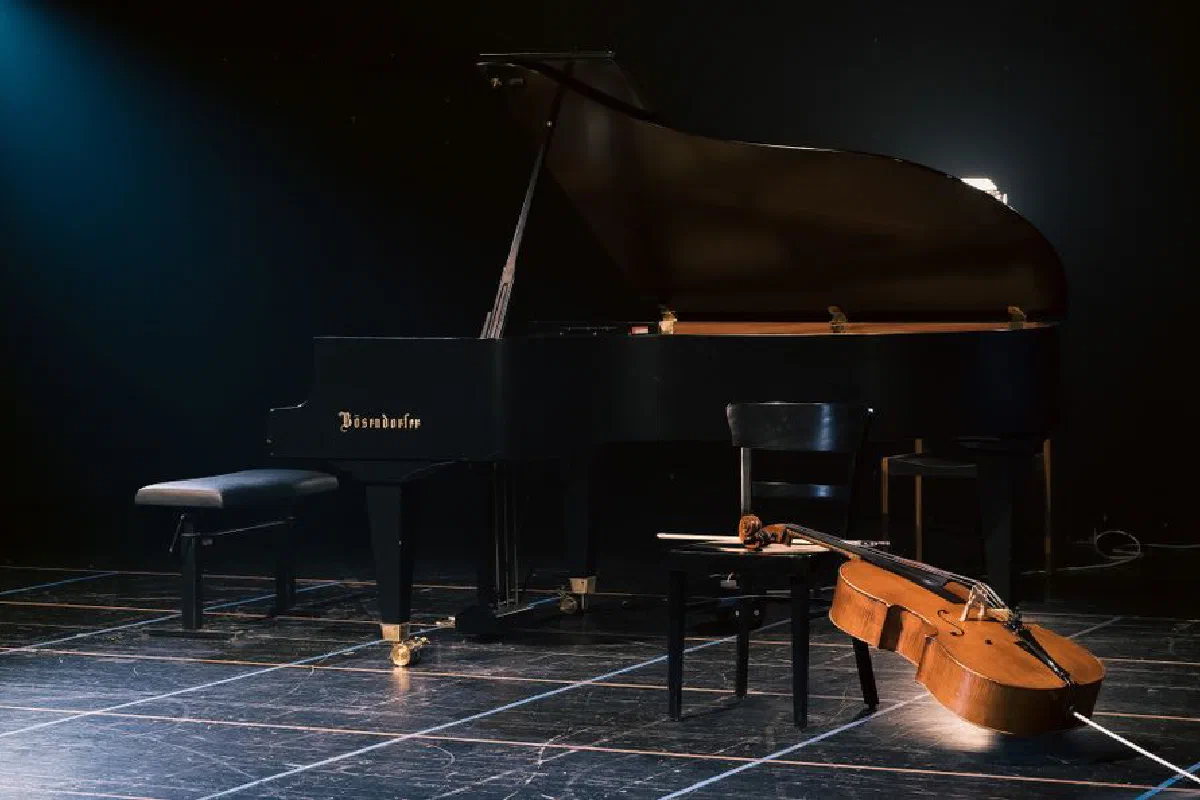 A grand piano and cello beautifully arranged on a dimly lit stage, capturing a serene musical moment.