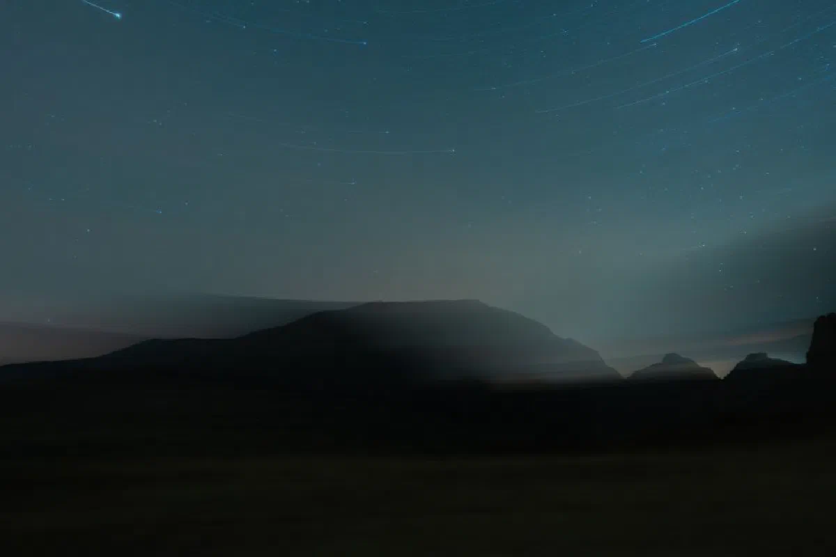 A serene starry night sky with star trails over silhouetted hills, capturing the calm beauty of nature.