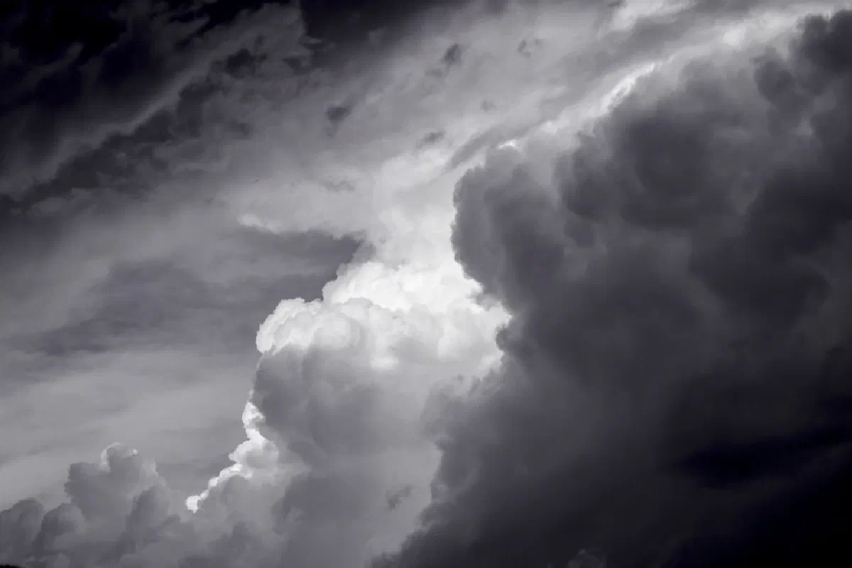 A striking black and white image capturing dramatic thunderstorm clouds in the sky.