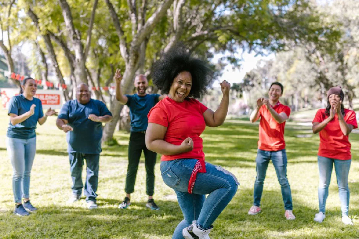 A diverse group enjoys a fun team-building activity in a sunny park setting.