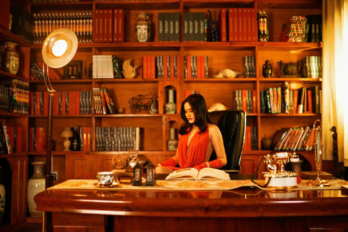A woman in an elegant home library reading a book, surrounded by bookshelves and a warm ambiance.