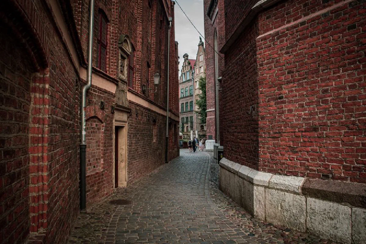 Explore a quaint cobblestone alleyway surrounded by historic brick buildings on a quiet day.