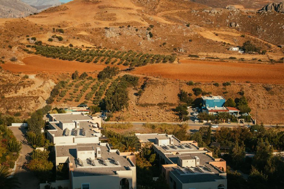 A bird's eye view of a village and fields in dry countryside, showcasing a sunny landscape.