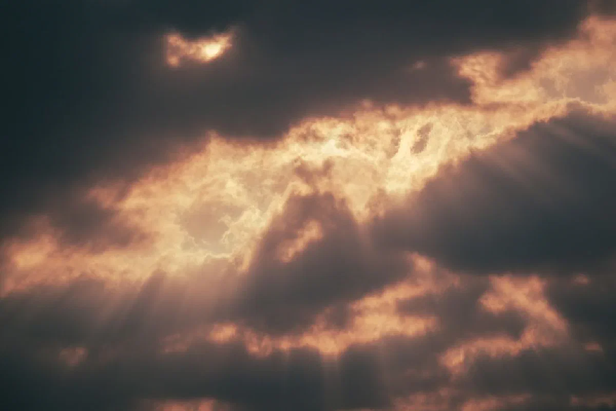 Sunlight piercing through dramatic dark clouds creating a mystical atmosphere.