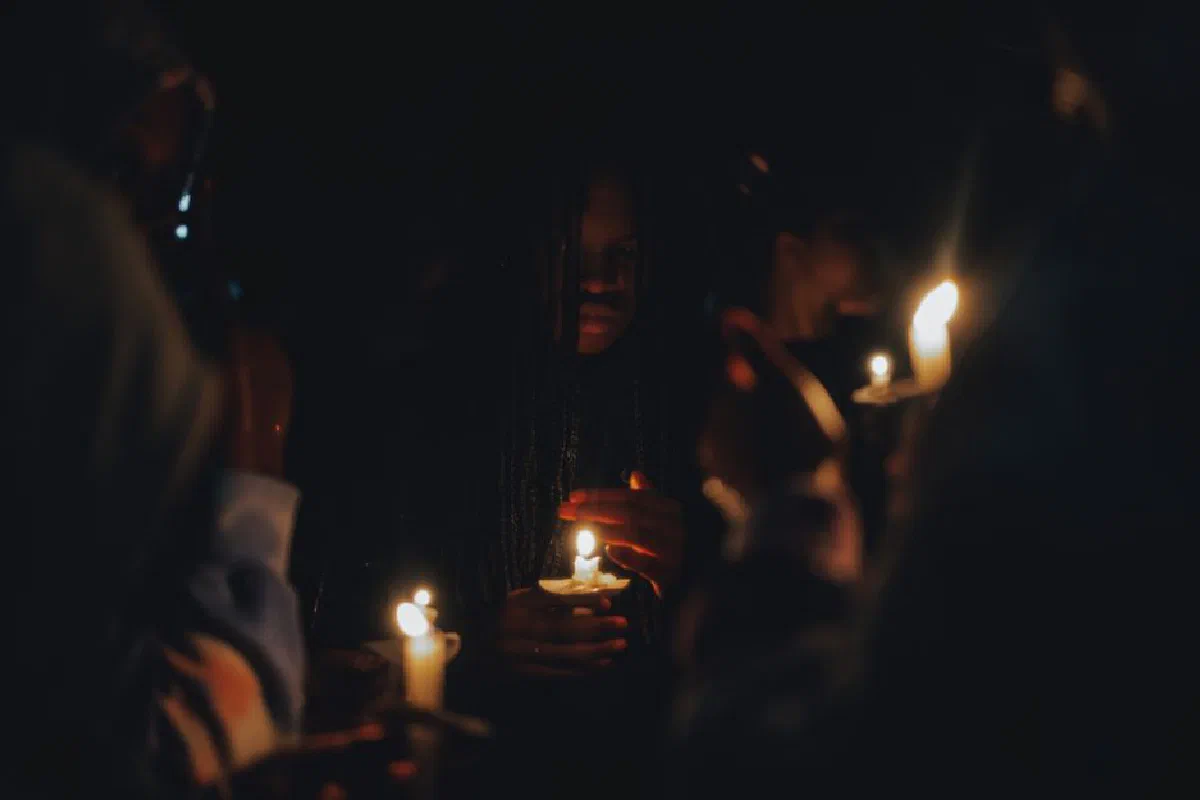 A solemn candlelit vigil at night with people holding lighted candles.