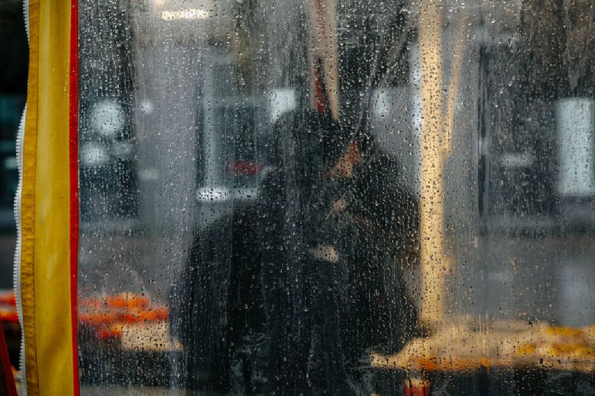 Silhouette seen through a rain-soaked window in Amsterdam market, creates a moody ambiance.