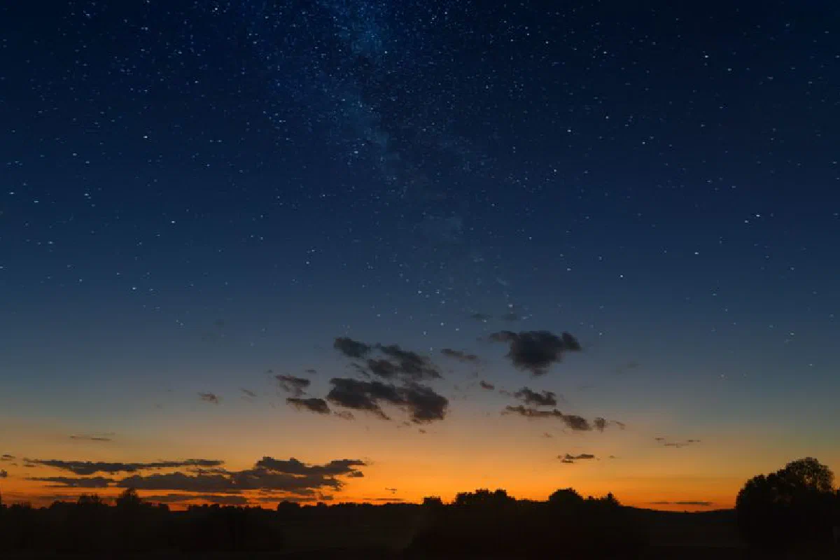Captivating starry night sky over a silhouette landscape at vibrant sunset.
