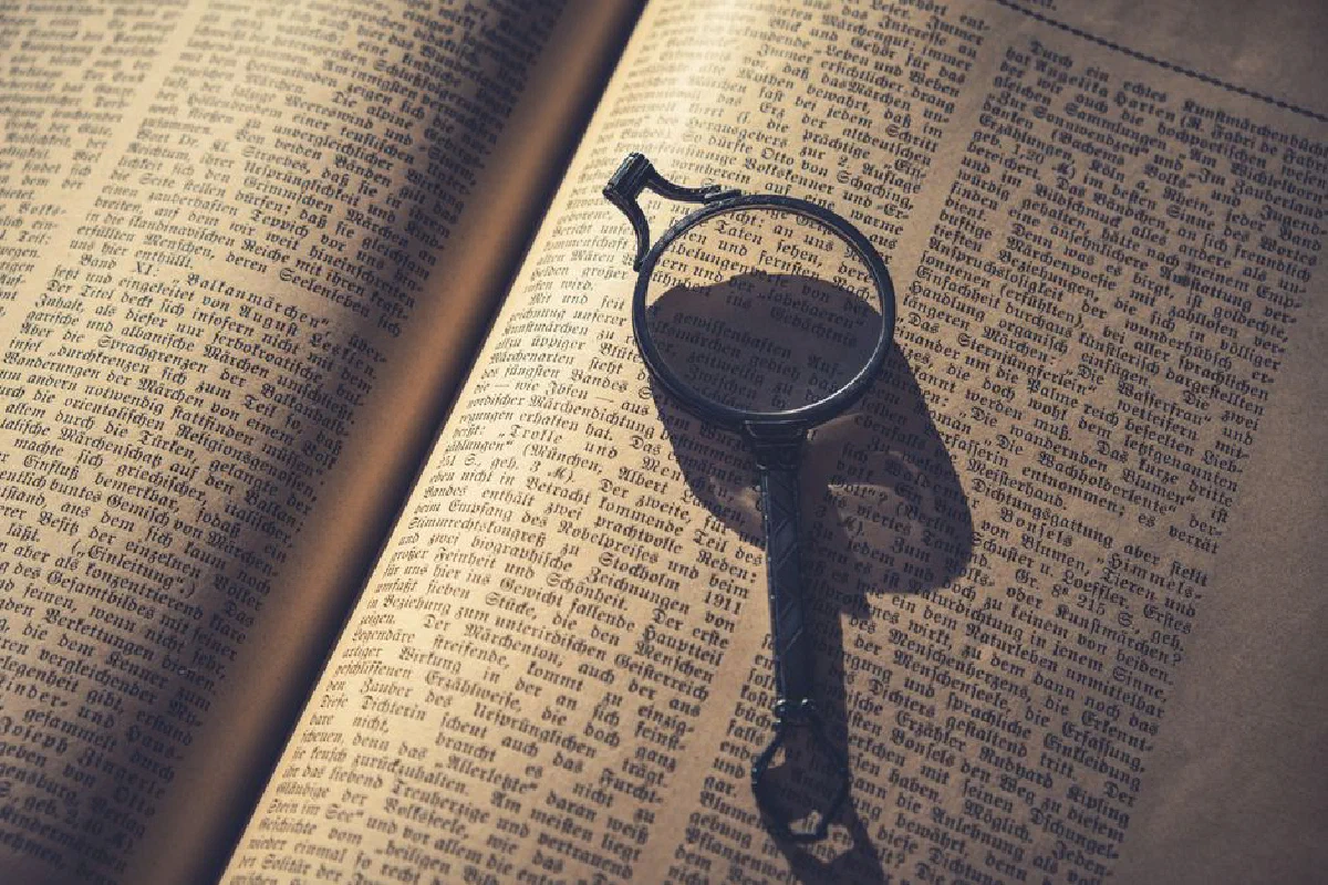 An old book with a magnifying glass highlighting text in warm lighting.