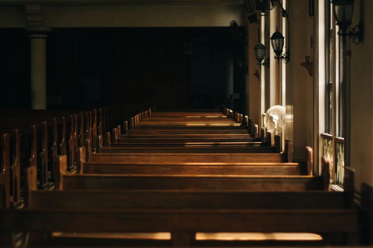 Serene church interior featuring wooden pews and beautiful lighting casting shadows through windows.