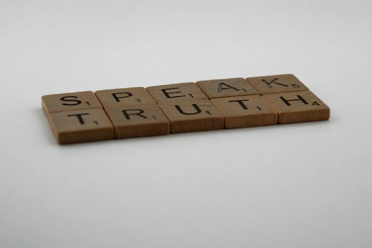 Wooden Scrabble tiles forming the phrase 'Speak Truth' on a white surface.