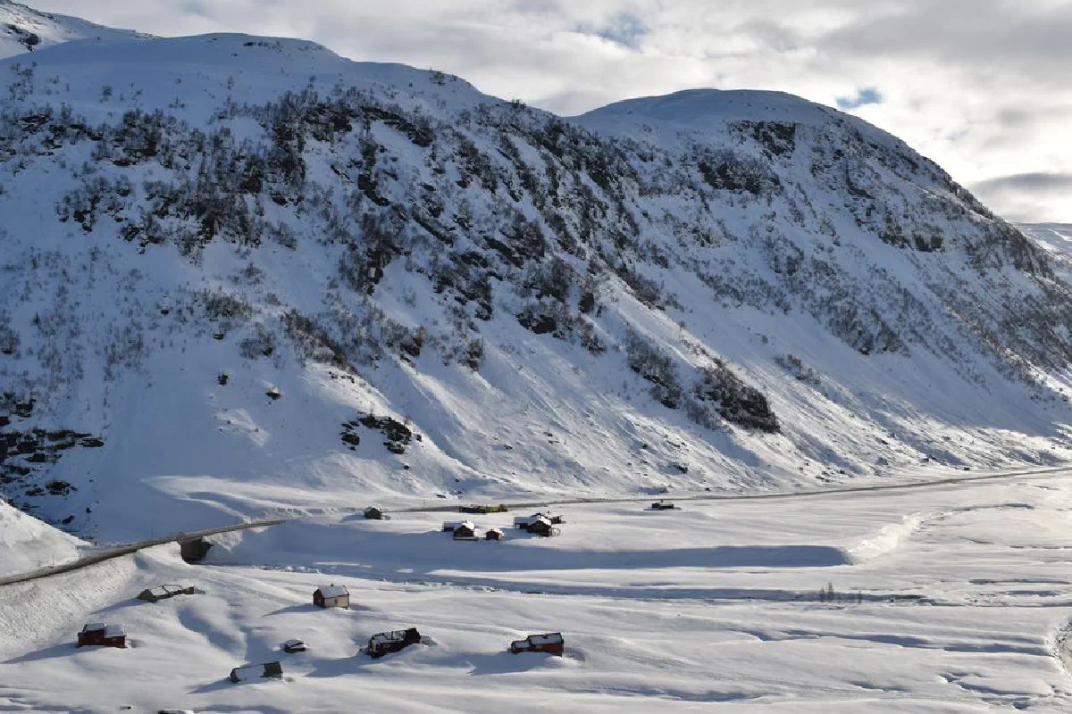 A breathtaking view of snow-covered mountains and a village in Norway, showcasing serene winter beauty.