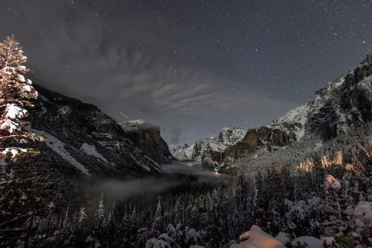 A stunning view of Yosemite Valley covered in snow under a starry night sky.