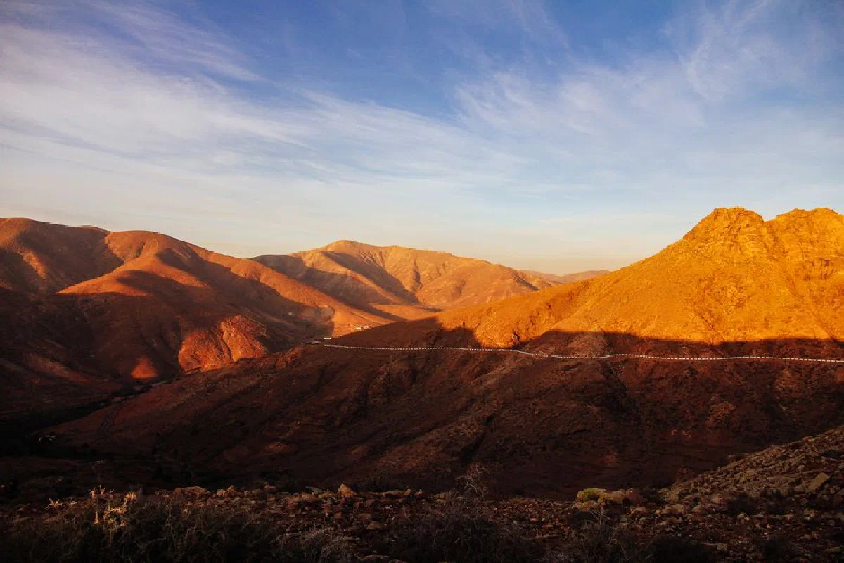 Capture of sunlit arid mountains at golden hour, showcasing natural desert landscape.