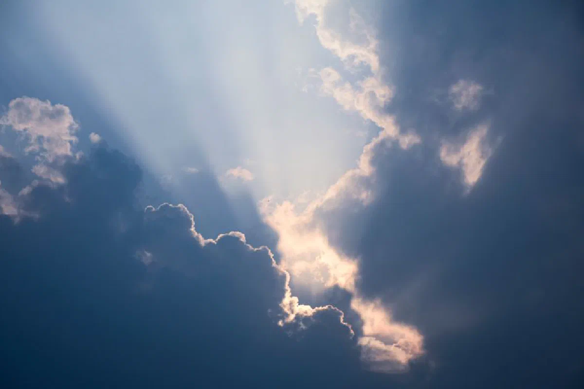 Sunrays breaking through dramatic clouds in a vibrant blue sky, showcasing a stunning cloudscape.
