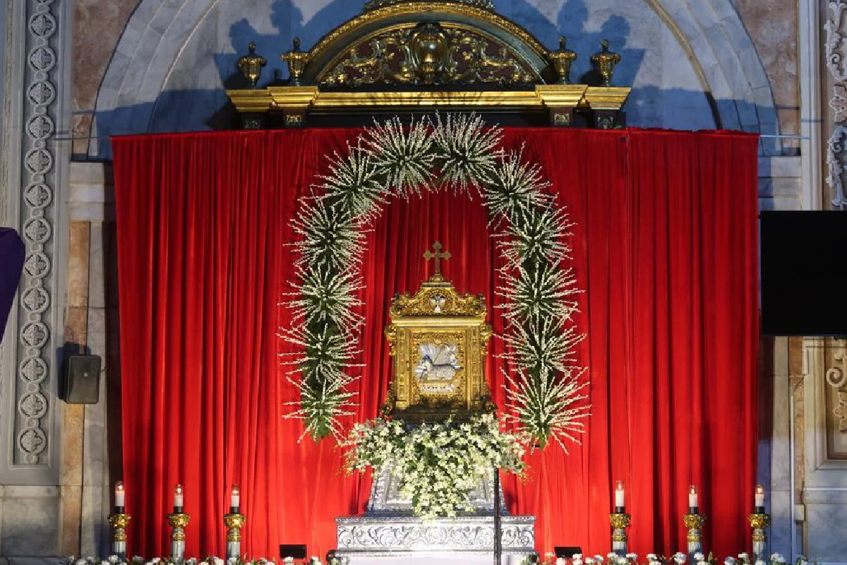 Intricate altar with gilded details and red drapery in a church in Manila, Philippines, showcasing floral decorations.