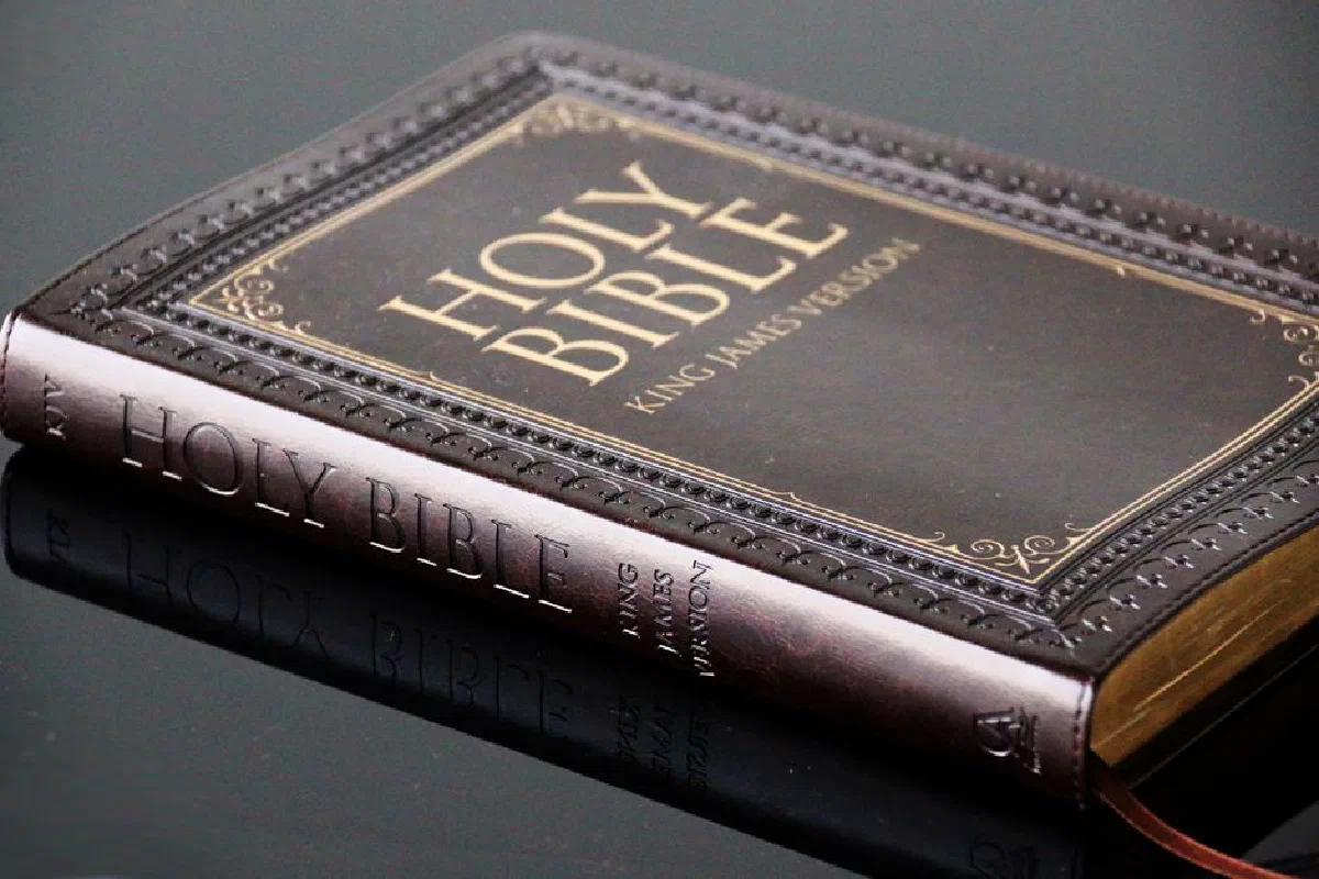 Close-up view of a leather bound King James Version Holy Bible resting on a reflective surface.