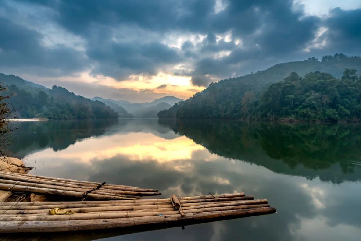 A tranquil scene of a river reflecting mountains and clouds at sunrise.