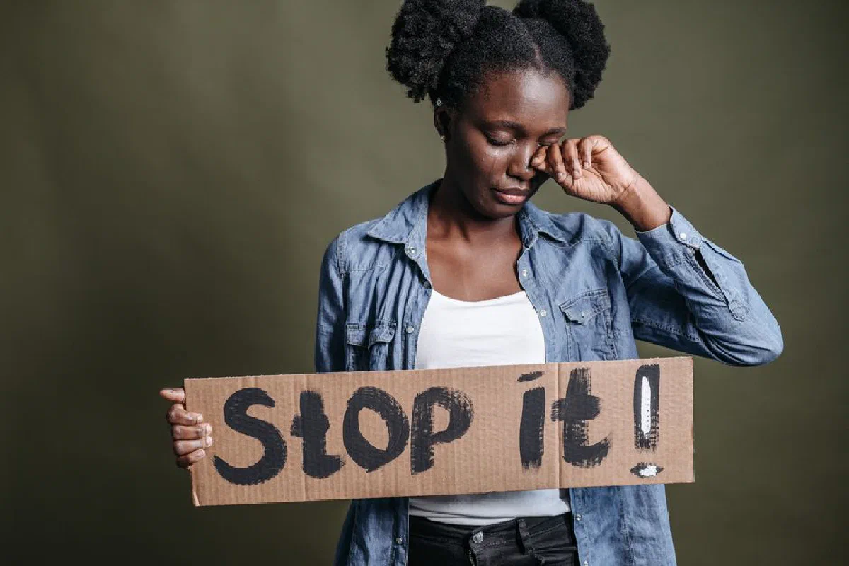 A woman tearfully holding a 'Stop it!' sign against racism in a powerful protest image.