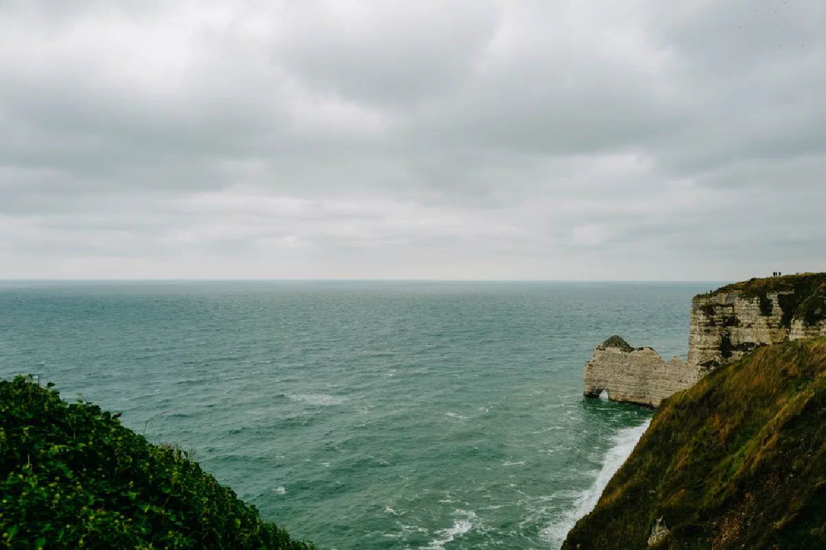 Explore the rugged cliffs and expansive ocean views under a moody overcast sky, capturing natural beauty.