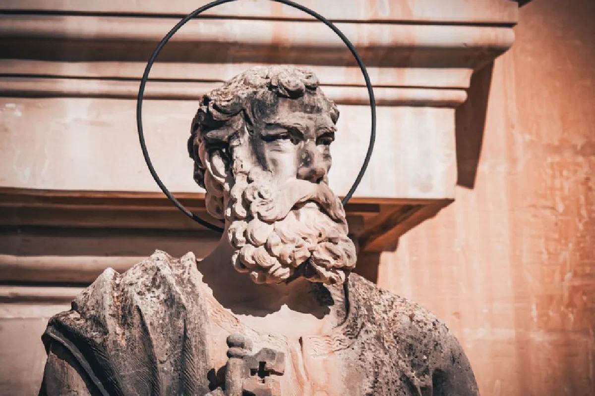 Detailed close-up of a weathered stone statue of a saint with a halo outside a historic church.