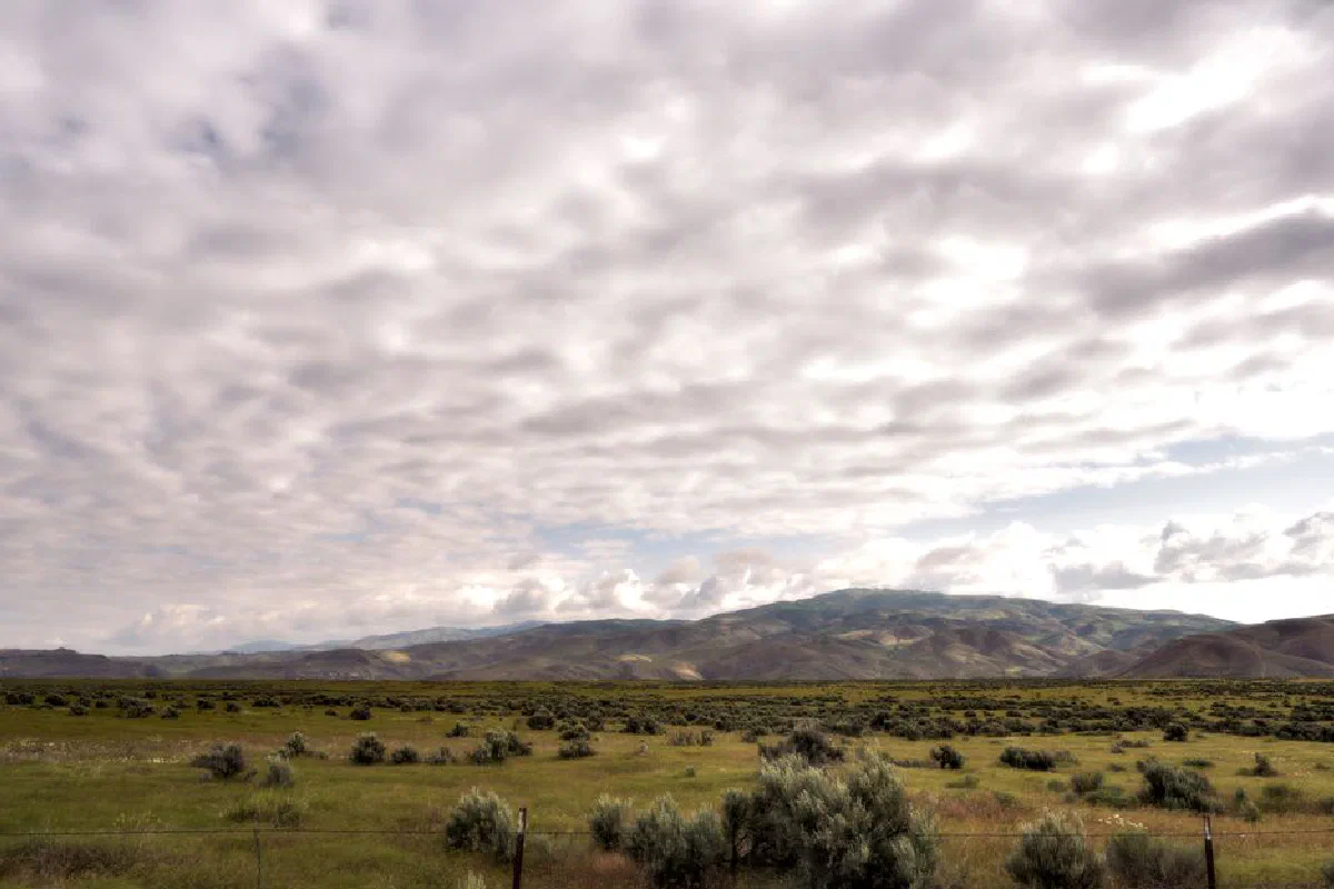 Vast cloudy sky above serene rolling hills and plains, depicting natural beauty.