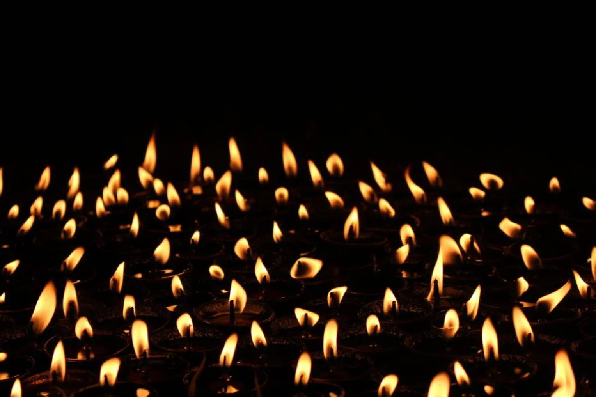 A captivating view of numerous wax candles with flames against a dark background, evoking warmth and tranquility.